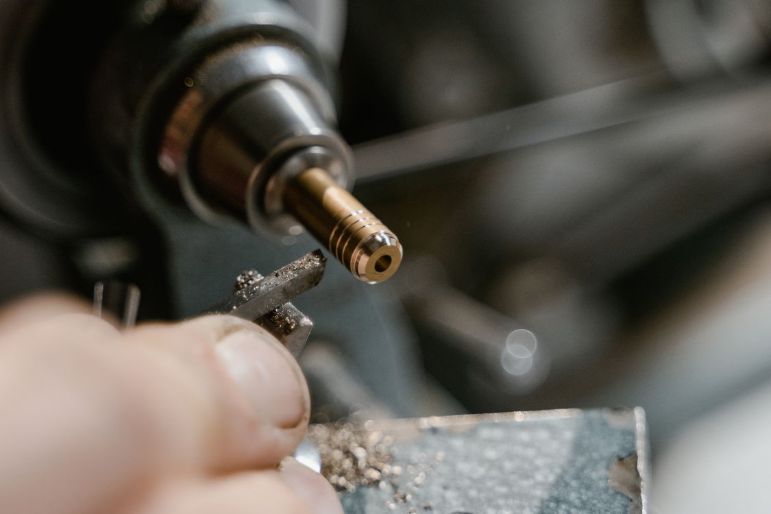 Close-up of a small cylindrical metal workpiece held in a lathe